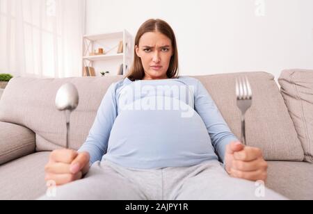 Faim pregnant woman Holding Spoon And Fork attendent de la nourriture à la maison. Nutrition de grossesse Concept Banque D'Images