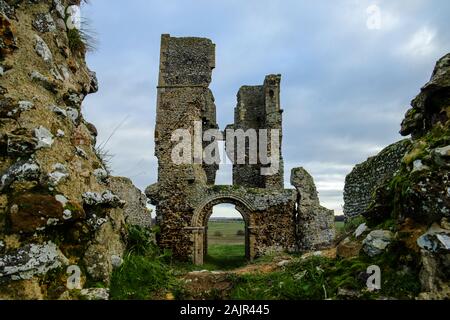 Pris à travers une brèche dans le mur, les ruines de l'église Saint-Jacques, Bawsey, Kings Lynn, Norfolk, Royaume-Uni. Sous un ciel couvert. Prise le 4 janvier 2020. Banque D'Images