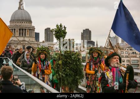 Londres, Royaume-Uni. 5e jan 2020. The Holly Man sur le pont du Millénaire. 25e congrès annuel de la Douzième Nuit de fête, une ancienne coutume de l'hiver, est tenue à Bankside, effectuée par la partie 'Lions' joueurs. L'homme, en bois de houx feuillage vert, est joué sur la Tamise. Il est rejoint par la London les mimes, de toasts (wassail) le peuple, et effectuer de combat folk freestyle jouer en costumes colorés. La procession se déplace de l'autre côté de la rivière, à Shakespeare's Globe et à la St George Inn, Southwark. Credit : Imageplotter/Alamy Live News Banque D'Images