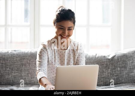 Smiling young woman working on laptop at home Banque D'Images