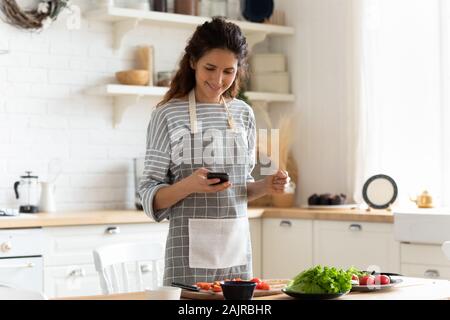 Woman holding smartphone à l'aide d'apps web recherche Recettes de cuisine Banque D'Images