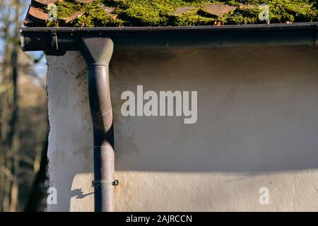 Gouttière le long d'une paroi d'une vieille maison avec de la mousse sur le toit en Allemagne Banque D'Images