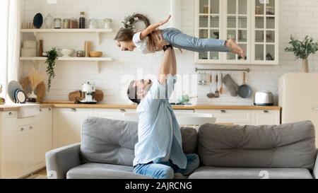 Père joyeux levage holding daughter having fun at home Banque D'Images