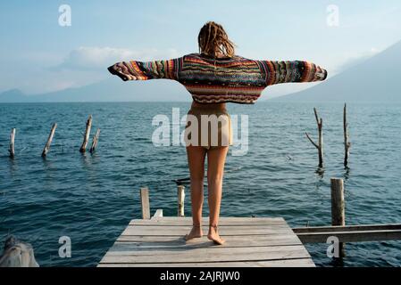 Vue arrière du Caucase attrayant femme dansant sur une jetée. Solo Outdoor lifestyle, vacances, voyages, loisirs concept. Lac Atitlan, Guatemala Banque D'Images