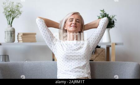 Heureux femme âgée vous détendre sur un canapé à la maison Banque D'Images