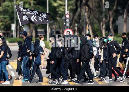 Hong Kong, Chine. 05Th Jan, 2020. Personnes brandissant le drapeau de protestation de "Hong Kong, révolution notre temps' en noir alors qu'il traversait la rue. Un dimanche à Sheung Shui contre le commerce parallèle qui visent à inciter les autorités à prendre des mesures à l'encontre des opérateurs parallèles qui de stock dans les boutiques locales puis tourner autour de les vendre pour le profit de l'autre côté de la frontière. Plus de cette marche de protestation depuis Hong Kong a commencé en juin et ressemblent souvent à un rassemblement anti-gouvernement. Credit : Geisler-Fotopress GmbH/Alamy Live News Banque D'Images