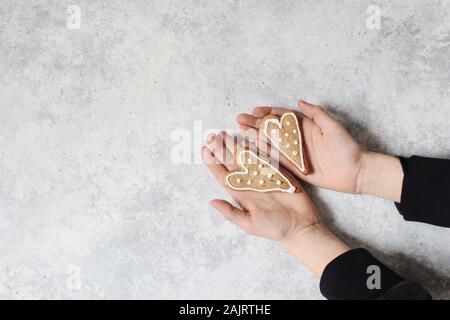 Les enfants de deux mains tenant le pain d'épice coeur cookies avec glaçage blanc. Valentin ou la fête des mères, jour de composition. Concept d'amour. Grunge backg Banque D'Images