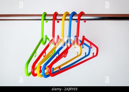 Cinq cintres en plastique multicolore sur une tige dans la penderie. Ensemble de nouveaux cintres en plastique coloré. Articles de maison. La vie domestique. Banque D'Images