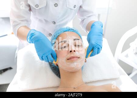 Portrait d'une belle jeune fille. Procédure pour l'application d'un masque de beauté pour le visage Soins de la peau et le rajeunissement. Un masque à l'aide de lavages coiffeur Yellow Banque D'Images