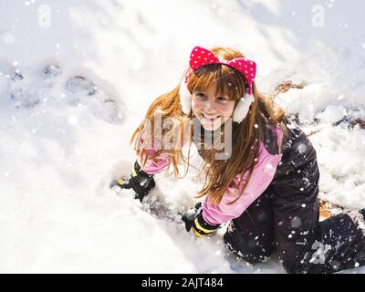 Petite rousse fille jouant avec de la neige en hiver Banque D'Images