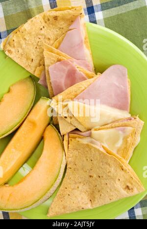 Sandwich wraps tortillas faites avec du jambon et fromage mozzarella basilic tomates séchées dans un pain de blé tortilla. Services avec le melon. Banque D'Images