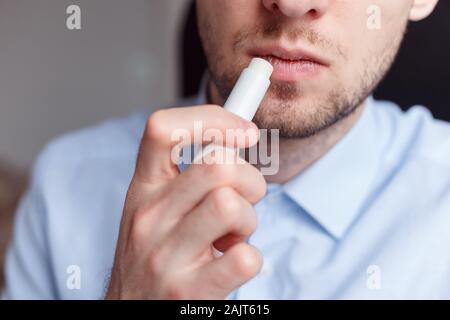 L'homme l'application de rouge à lèvres sur les lèvres d'hygiène à relancer des lèvres gercées et éviter les gros plan, sec Banque D'Images