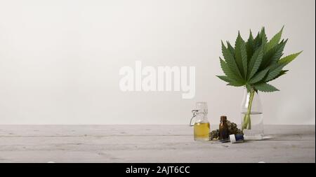 Banner montrant CBD huile dans le flacon en verre, la marijuana cannabis sativa feuilles des mauvaises herbes et flacon compte-gouttes, sur rez-de-chaussée en bois industriel Banque D'Images