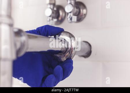 Plombier universel chrome maintient sur l'écusson du tuyau siphon sous le lavabo. Plombier au travail dans la salle de bains, plomberie Montage et pose concept Banque D'Images