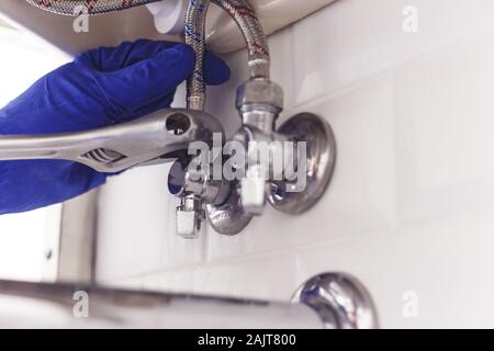 Plombier tours sur l'écrou de la soupape d'angle sous lavabo à l'aide de la diffusion d'une clé dynamométrique. Banque D'Images