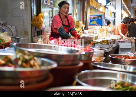 Une femme coréenne mature met des gants en caoutchouc pour servir Kimchi au marché de Gwangjang à Séoul, en Corée du Sud. Banque D'Images