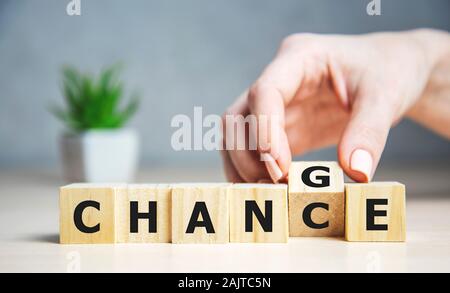 Businesswoman holding cube de bois avec plus de changement de bloc au hasard mot sur arrière-plan du tableau. succès, stratégie, solution, business et Banque D'Images