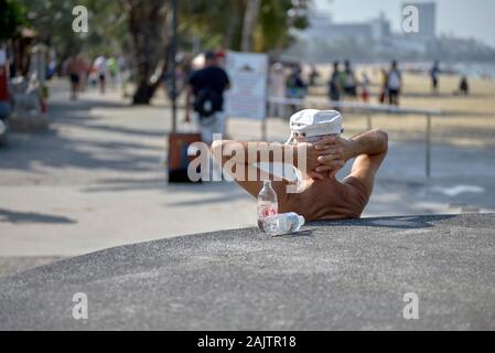 Détente homme avec les mains derrière la tête et en admirant la vue sur Pattaya Beach Road, la Thaïlande Asie du sud-est Banque D'Images