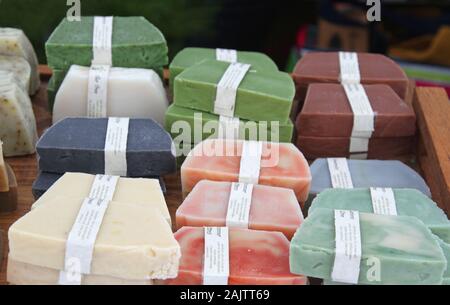 Les savons artisanaux colorés avec des ingrédients marqués sur bandes blanches dans un marché Banque D'Images