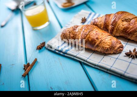 Petit-déjeuner traditionnel français, crissant et café et jus sur table en bois bleu Banque D'Images