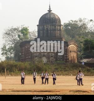 Bishnupur, Bengale de l'Ouest, Inde - 6 février 2018: Les enfants de retour de l'école, l'ancien temple Radha Shyam en arrière-plan. Banque D'Images