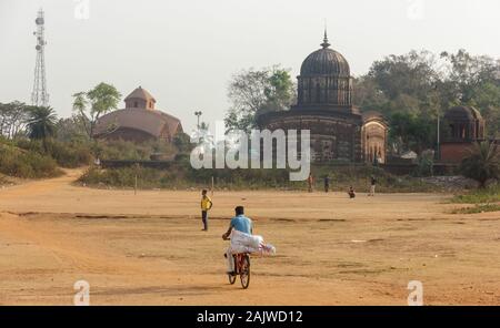 Bishnupur, Bengale de l'Ouest/Inde - 6 février 2018: Un homme se met à vélo avec ses bagages sur le sol à l'extérieur de l'ancien temple hindou de Radha Shyam. Banque D'Images