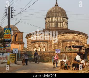 Bishnupur, Bengale de l'Ouest, Inde - 6 février 2018 : façade extérieure de l'ancien temple Radha Shyam. Les gens s'assoient dans un café en bordure de la route à l'extérieur. Banque D'Images