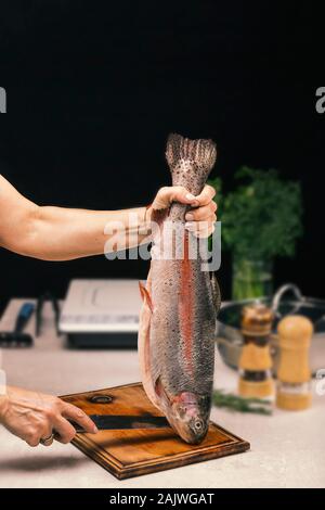 Femme détient le saumon dans les mains. Cook femme cuire le saumon. Concept de cuisson. Banque D'Images