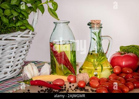 Les bouteilles avec de l'huile aromatisée. Saveurs de l'Italie. Le basilic, le poivre et l'ail. La préparation d'une salade.. Les tomates et saveurs de pizza. Banque D'Images