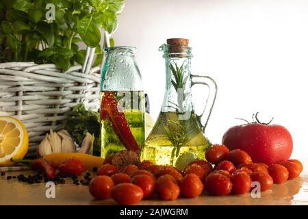 Les bouteilles avec de l'huile aromatisée. Saveurs de l'Italie. Le basilic, le poivre et l'ail. La préparation d'une salade.. Les tomates et saveurs de pizza. Banque D'Images