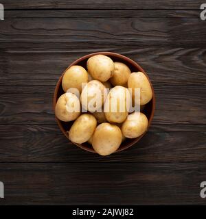 Les jeunes pommes de terre non pelées dans un bol sur une table en bois sombre. Banque D'Images