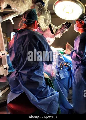 Deux chirurgiens effectuer une chirurgie dans l'obscurité de la salle d'opération (microchirurgie pour AVC) Banque D'Images