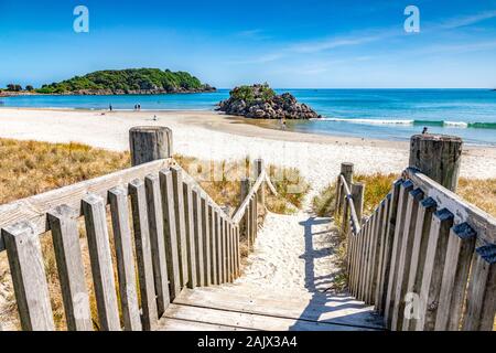 9 décembre 2018 : Mount Maunganui, Bay of Plenty, Nouvelle-Zélande - marches à descendre à la plage sur une belle journée d'été, avec une petite île et des gens qui marchent.. Banque D'Images