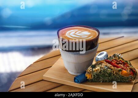 Une tasse de café avec un morceau de tarte aux légumes sur une table, arrière-plan flou Banque D'Images