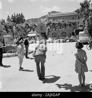 Années 1950, historiques, des cotes de sur, la France, l'été, et un homme et des enfants dans la place d'un village à l'boules, un jeu traditionnel français avec boules métalliques playe sur une surface de terre. Un jeu populaire, semblable à la pétanque, il est également connu comme la pétanque. Banque D'Images