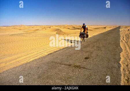 Cycliste solitaire errant entre sanddunes sur la route entre Taftan et Quetta Banque D'Images