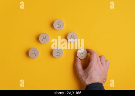 Placer la main masculine coupe de bois rond avec icône personne sur eux en pyramide. Sur fond jaune. Banque D'Images