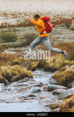 Man jumping over river en montagne randonnée aventure voyage de vie actif en plein air vacances en Norvège Banque D'Images