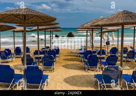 Destination vacances d'été. Les parasols de paille et de chaises longues sur la plage de galets vide avec la mer en arrière-plan. Vacances et Tourisme Concept. Transats O Banque D'Images