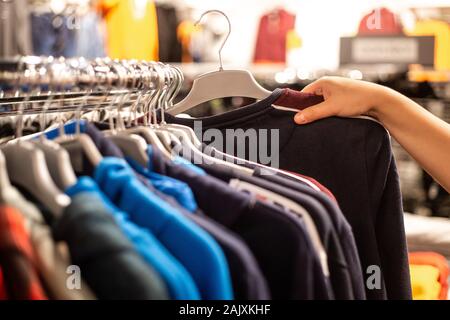 Jeune femme choisissant les vêtements dans l'immense centre commercial au cours de grandes ventes Banque D'Images