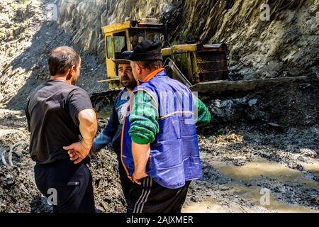 Omalo, Géorgie - 11 juin 2016 : les travailleurs avec le tracteur déposer le glissement de terrain sur la route de montagne, Tusheti Banque D'Images