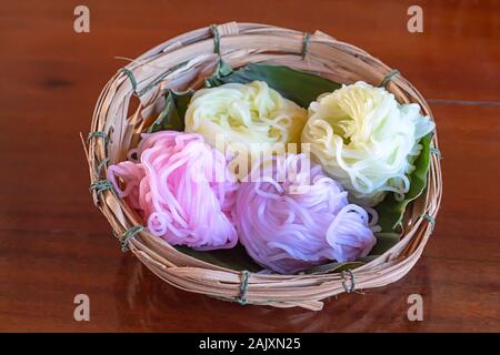 Nouilles de riz coloré sur une feuille de bananier dans un panier de bambou sur la table. Banque D'Images