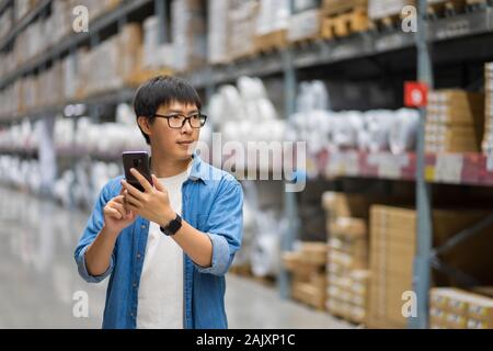 Portrait Asian men, du personnel, des produits de contrôle d'entrepôt permanent Gestionnaire comptage, comptage et contrôle des produits dans l'entrepôt Banque D'Images