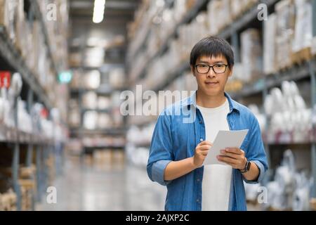 Portrait Asian men, du personnel, des produits de contrôle d'entrepôt permanent Gestionnaire comptage, comptage et contrôle des produits dans l'entrepôt Banque D'Images