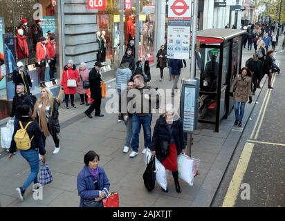 Les personnes portant des vêtements d'hiver shoppers debout en attente d'un bus à un arrêt de bus à l'extérieur de magasin Uniqlo dans Oxford Street London England UK KATHY DEWITT Banque D'Images