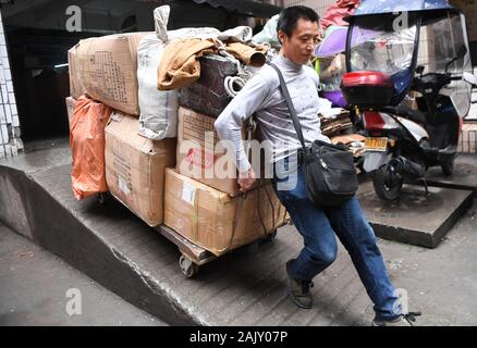 (200106) -- CHONGQING, le 6 janvier 2020 (Xinhua) -- Ran Guanghui déplace marchandises hors d'un centre commercial à Chaotianmen dans le sud-ouest de la Chine, la municipalité de Chongqing, le 5 janvier 2020. Ran Guanghui, 50 ans, a gagné sa vie comme un "bang bang", littéralement "rester les hommes", à Chongqing pendant dix ans. Dans une ville de montagne comme Chongqing, avec une abondance de routes vallonnées et de sentiers, stick men ont aidé les personnes par transport des bagages et objets lourds. Transporter des marchandises sur les poteaux de bambou en équilibre sur leurs épaules, le bâton du pain gagné les hommes à la sueur de leur front. Ran est devenu l'un d'entre eux en 2009 lorsqu'il a quitté son Banque D'Images