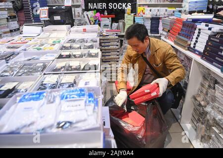 (200106) -- CHONGQING, le 6 janvier 2020 (Xinhua) -- Ran Guanghui prend les marchandises dans un centre commercial à Chaotianmen dans le sud-ouest de la Chine, la municipalité de Chongqing, le 5 janvier 2020. Ran Guanghui, 50 ans, a gagné sa vie comme un "bang bang", littéralement "rester les hommes", à Chongqing pendant dix ans. Dans une ville de montagne comme Chongqing, avec une abondance de routes vallonnées et de sentiers, stick men ont aidé les personnes par transport des bagages et objets lourds. Transporter des marchandises sur les poteaux de bambou en équilibre sur leurs épaules, le bâton du pain gagné les hommes à la sueur de leur front. Ran est devenu l'un d'entre eux en 2009 lorsqu'il a quitté son h Banque D'Images