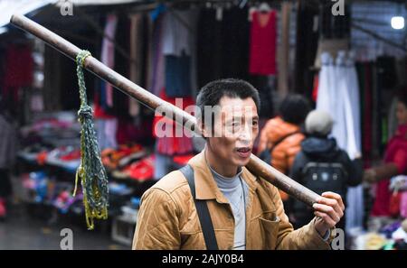 (200106) -- CHONGQING, le 6 janvier 2020 (Xinhua) -- Ran Guanghui cherche des clients près de Chaotianmen, dans le sud-ouest de la municipalité de Chongqing en Chine, le 5 janvier 2020. Ran Guanghui, 50 ans, a gagné sa vie comme un "bang bang", littéralement "rester les hommes", à Chongqing pendant dix ans. Dans une ville de montagne comme Chongqing, avec une abondance de routes vallonnées et de sentiers, stick men ont aidé les personnes par transport des bagages et objets lourds. Transporter des marchandises sur les poteaux de bambou en équilibre sur leurs épaules, le bâton du pain gagné les hommes à la sueur de leur front. Ran est devenu l'un d'entre eux en 2009 lorsqu'il a quitté sa ville natale de Diam Banque D'Images