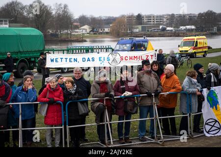 Brême, Allemagne. 08Th Jan, 2020. Les militants du mouvement de rébellion d'Extinction démontrer avec une affiche avec l'inscription 'Wetten das, Eismelzt !' à côté du lieu de la glace de Brême pari. Credit : Sina Schuldt/dpa/Alamy Live News Banque D'Images