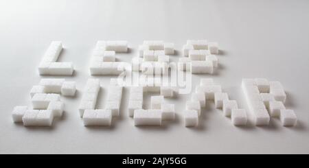 "Moins de sucre' écrit avec pixel art lettres faites de morceaux de sucre sur un fond blanc Banque D'Images